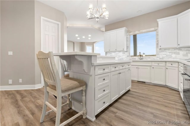 275 Waterford Ter, Sunrise Beach, MO 65079 - kitchen with white cabinetry, a kitchen breakfast bar, tasteful backsplash, and light countertops
