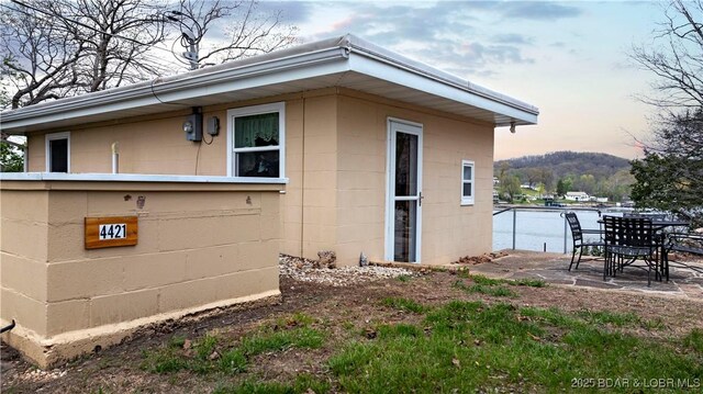 view of property exterior with concrete block siding, a patio area, and outdoor dining space