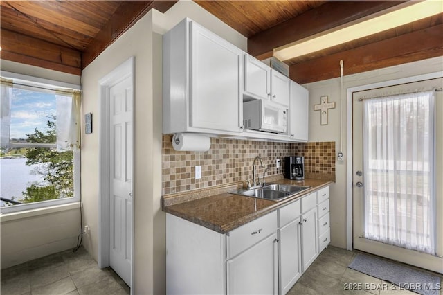 kitchen featuring wooden ceiling, decorative backsplash, a sink, and white microwave