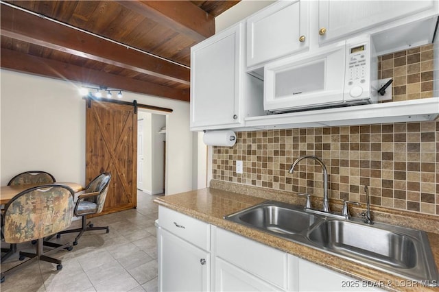 kitchen with white microwave, white cabinetry, wooden ceiling, and decorative backsplash