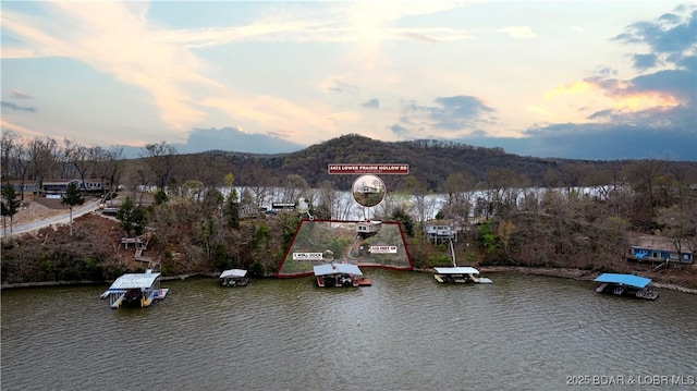 aerial view at dusk featuring a water and mountain view
