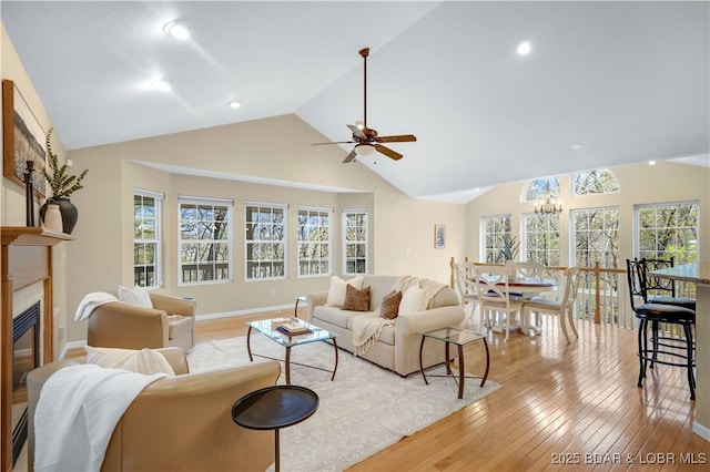 101 Cliffstone Ln, Sunrise Beach, MO 65079 - living area with lofted ceiling, a ceiling fan, light wood-style floors, a chandelier, and a glass covered fireplace