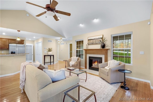 101 Cliffstone Ln, Sunrise Beach, MO 65079 - living room with a ceiling fan, a fireplace with flush hearth, light wood-style flooring, baseboards, and high vaulted ceiling