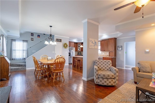 dining area with crown molding, baseboards, stairs, dark wood-style flooring, and ceiling fan with notable chandelier