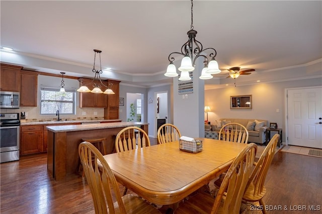 dining room featuring crown molding, ceiling fan with notable chandelier, and dark wood finished floors