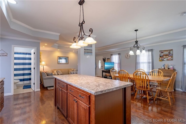 kitchen featuring open floor plan, light countertops, a kitchen island, dark wood-type flooring, and hanging light fixtures