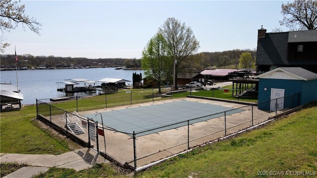 pool with a lawn, a water view, and fence