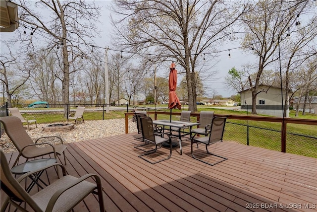 deck featuring a yard, fence, outdoor dining space, and an outdoor fire pit