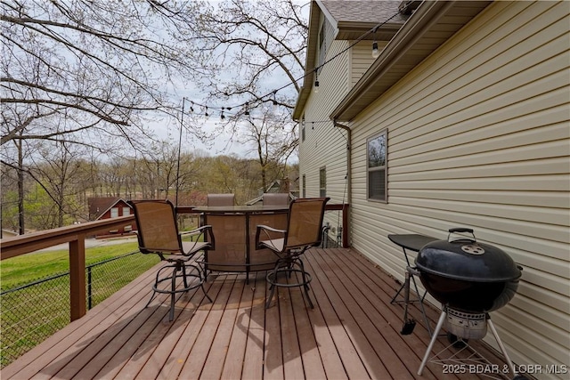 wooden terrace featuring a lawn and a grill
