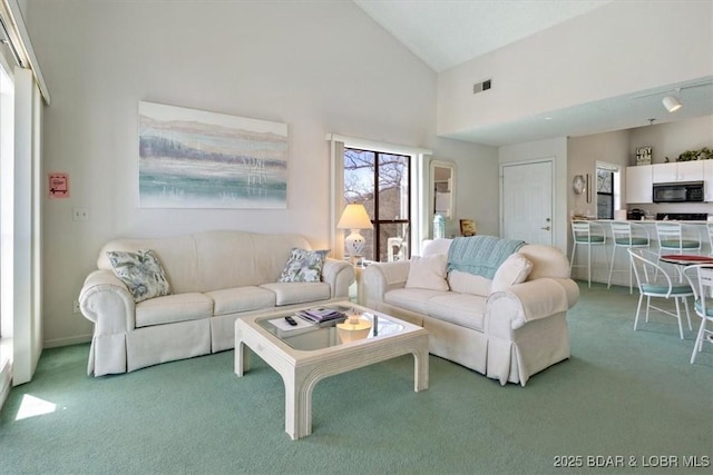 carpeted living area featuring visible vents and high vaulted ceiling