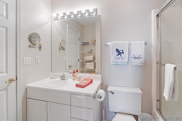 bathroom with vanity, a shower with door, and toilet