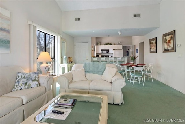 carpeted living area with visible vents and a high ceiling