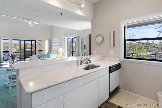 kitchen featuring dishwasher, a healthy amount of sunlight, a sink, a peninsula, and open floor plan