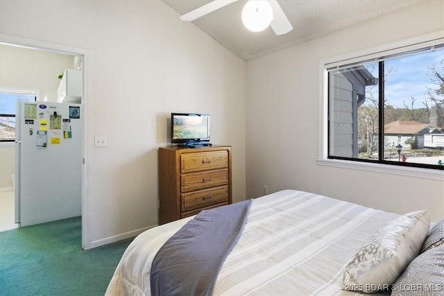 carpeted bedroom featuring freestanding refrigerator, vaulted ceiling, and ceiling fan