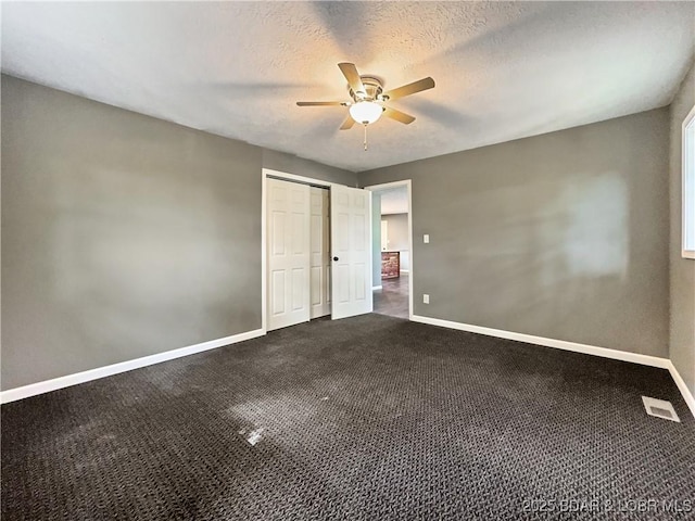 3053 Doc Ridgeway Dr, Roach, MO 65787 - unfurnished bedroom with baseboards, dark carpet, a ceiling fan, a closet, and a textured ceiling