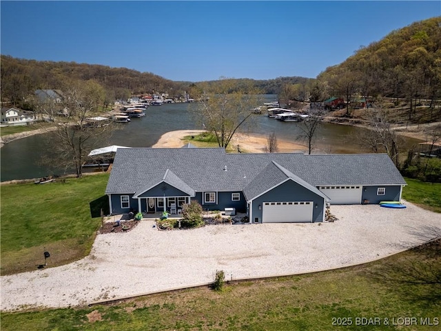 view of front of home with an attached garage, driveway, a water view, and a porch
