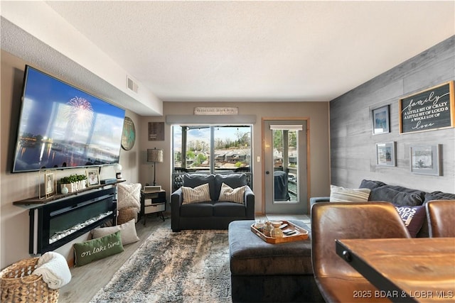 living room with an accent wall, wood finished floors, and visible vents