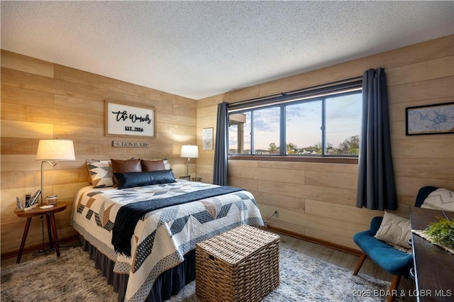 bedroom featuring wooden walls, wood finished floors, and a textured ceiling