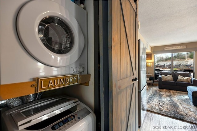 laundry area featuring stacked washer / drying machine, a textured ceiling, and laundry area