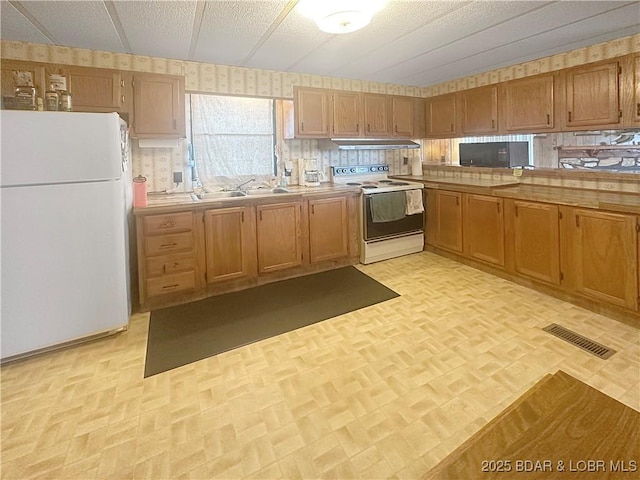 796 1051st Rd SE, Mo, MO 64740 - kitchen with a sink, wallpapered walls, white appliances, under cabinet range hood, and visible vents