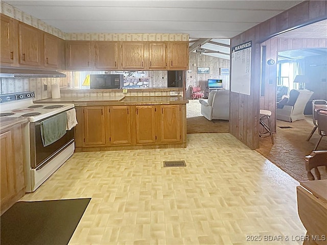 796 1051st Rd SE, Mo, MO 64740 - kitchen featuring a peninsula, visible vents, wood walls, range hood, and white range with electric cooktop