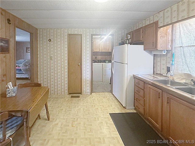 796 1051st Rd SE, Mo, MO 64740 - kitchen with wallpapered walls, freestanding refrigerator, a sink, and separate washer and dryer