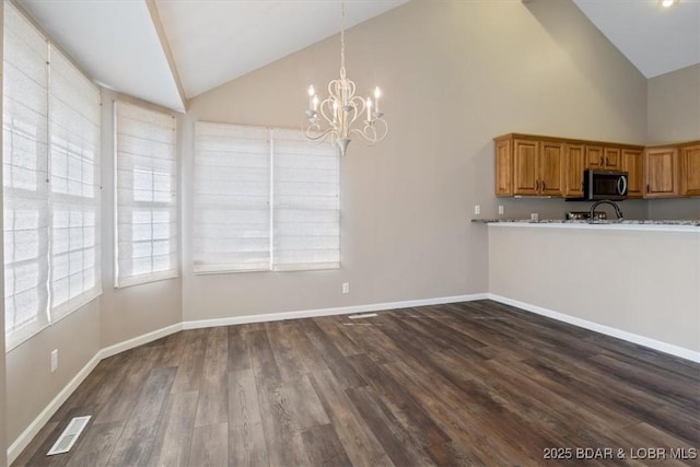 kitchen featuring stainless steel microwave, a chandelier, high vaulted ceiling, dark wood-style floors, and baseboards