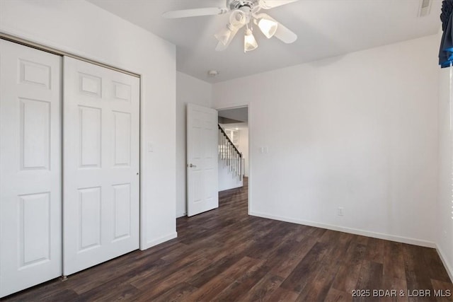 unfurnished bedroom with dark wood-style floors, baseboards, a closet, and a ceiling fan