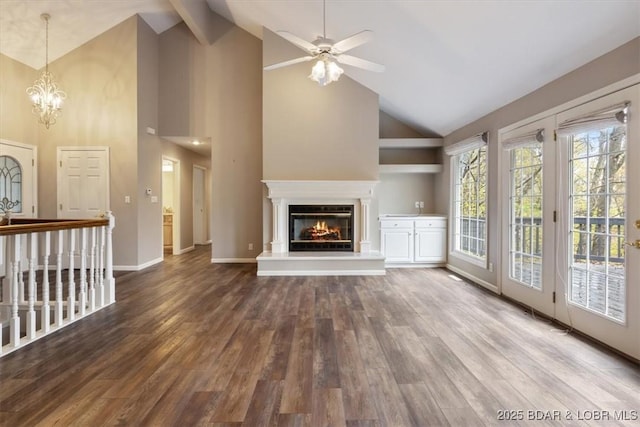 unfurnished living room with high vaulted ceiling, wood finished floors, a ceiling fan, a glass covered fireplace, and a chandelier