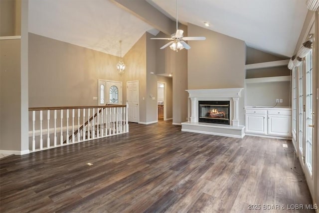 unfurnished living room with high vaulted ceiling, a ceiling fan, dark wood-type flooring, a glass covered fireplace, and a chandelier