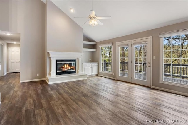 unfurnished living room with a ceiling fan, wood finished floors, plenty of natural light, and high vaulted ceiling