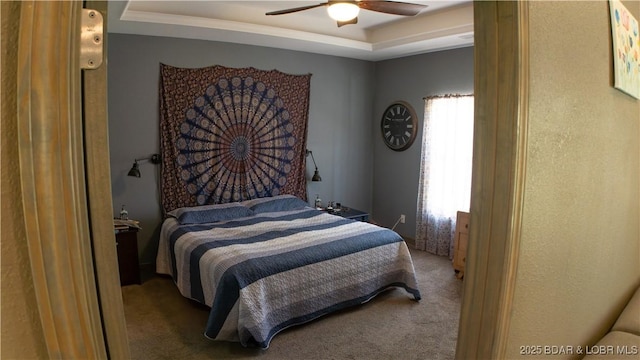 bedroom featuring a tray ceiling, carpet, and ceiling fan