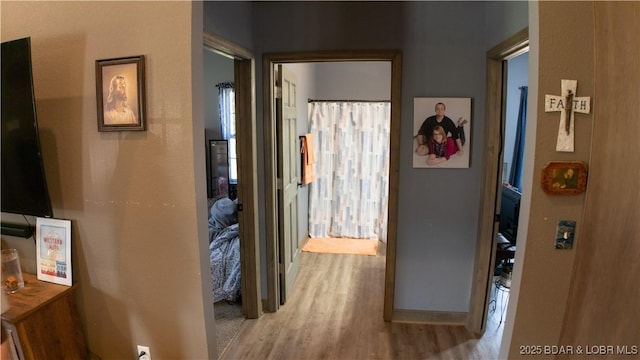 corridor featuring baseboards and light wood finished floors