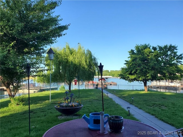 view of community featuring a yard, fence, and a water view