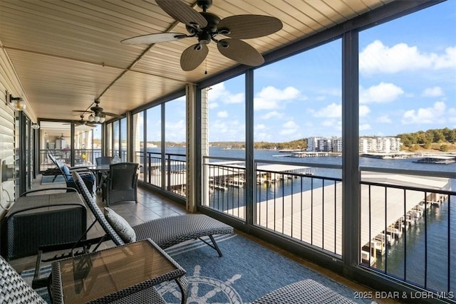 sunroom / solarium featuring a ceiling fan and a water view