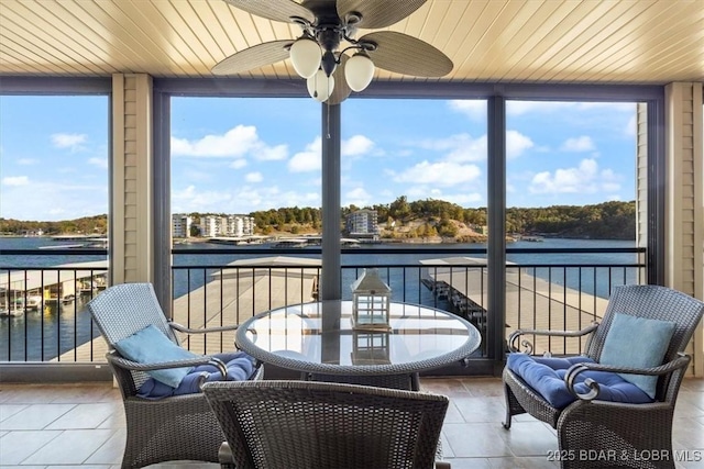 sunroom / solarium featuring wooden ceiling, tile patterned floors, and a water view
