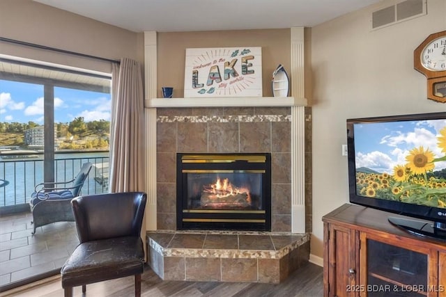 living area with a fireplace, wood finished floors, and visible vents