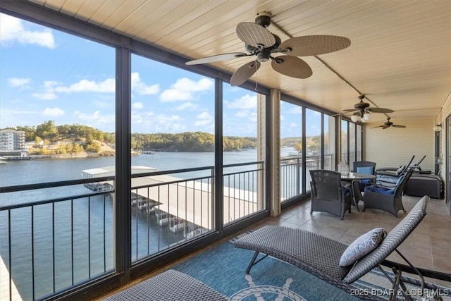 sunroom / solarium featuring a ceiling fan and a water view