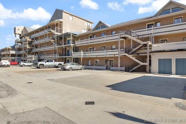 view of property with stairway and uncovered parking