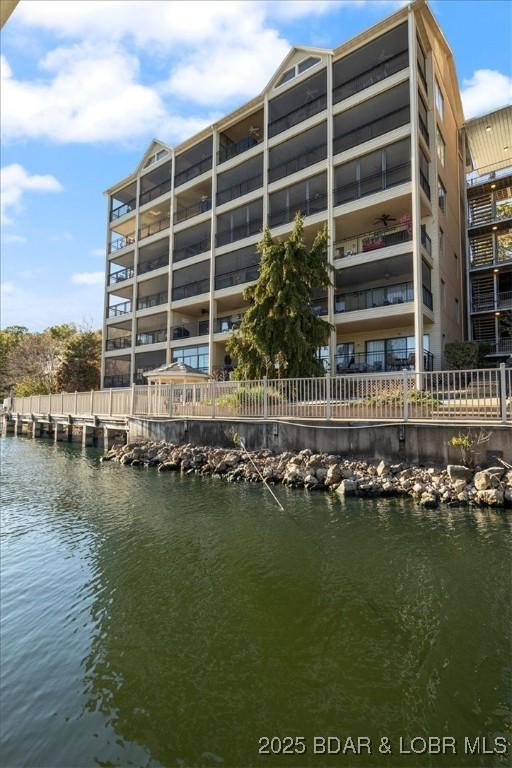 view of building exterior with fence and a water view