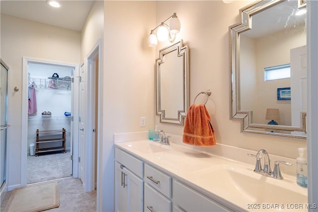 bathroom with a spacious closet, double vanity, a shower stall, and recessed lighting