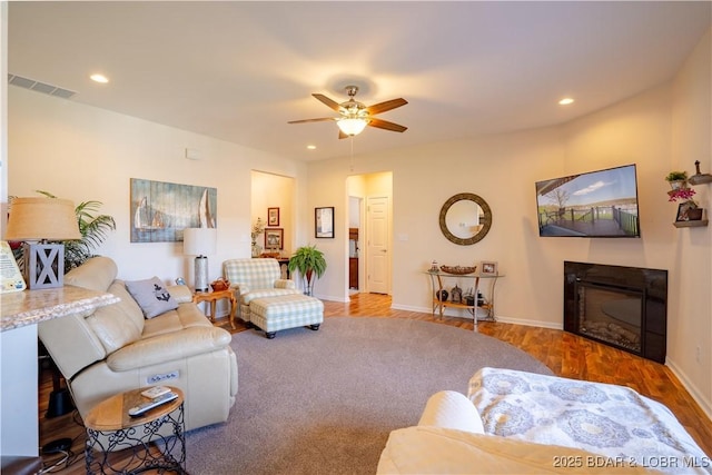 living room featuring a ceiling fan, a glass covered fireplace, baseboards, recessed lighting, and wood finished floors