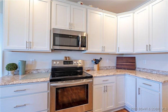 kitchen featuring stainless steel appliances, white cabinetry, and light stone countertops