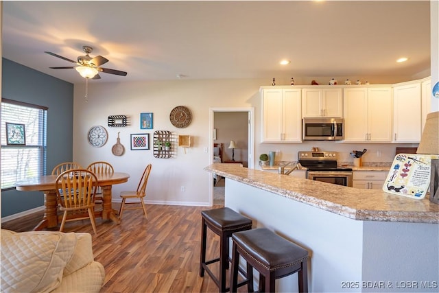 kitchen featuring appliances with stainless steel finishes, baseboards, wood finished floors, light countertops, and recessed lighting