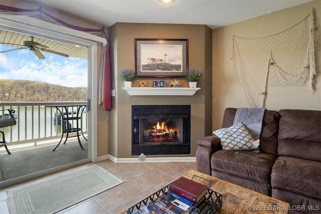 4800 Eagleview Dr Unit 133, Osage Beach, MO 65065 - living room featuring a glass covered fireplace, a ceiling fan, tile patterned flooring, and baseboards