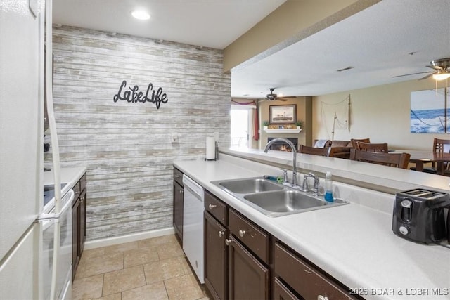 4800 Eagleview Dr Unit 133, Osage Beach, MO 65065 - kitchen with a ceiling fan, a sink, white appliances, a warm lit fireplace, and wooden walls