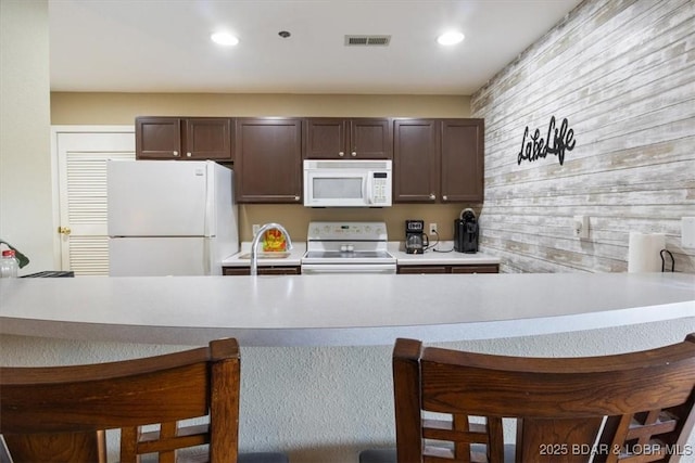 4800 Eagleview Dr Unit 133, Osage Beach, MO 65065 - kitchen with white appliances, dark brown cabinetry, a kitchen breakfast bar, a peninsula, and recessed lighting