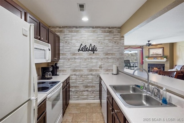 4800 Eagleview Dr Unit 133, Osage Beach, MO 65065 - kitchen featuring white appliances, a sink, a ceiling fan, a warm lit fireplace, and wood walls