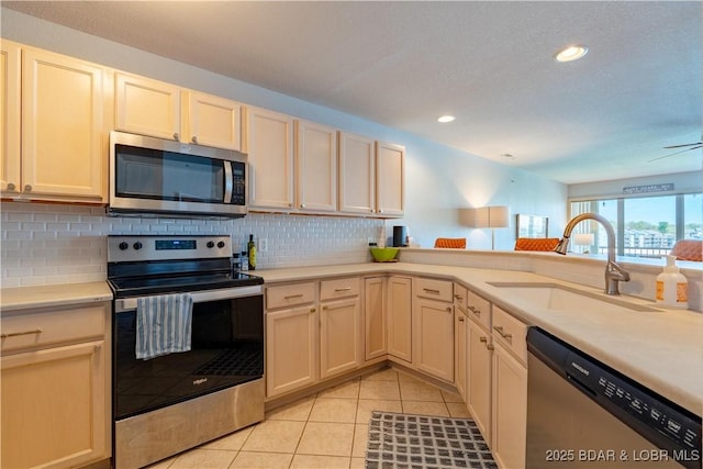 245 Bristol Bay Dr Unit 2B, Lake Ozark, MO 65049 - kitchen featuring stainless steel appliances, a sink, decorative backsplash, light tile patterned floors, and light countertops