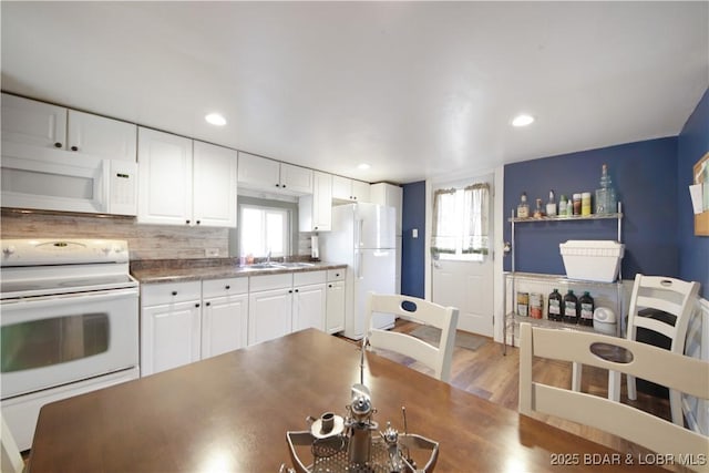 kitchen with white cabinets, a healthy amount of sunlight, a sink, and white appliances
